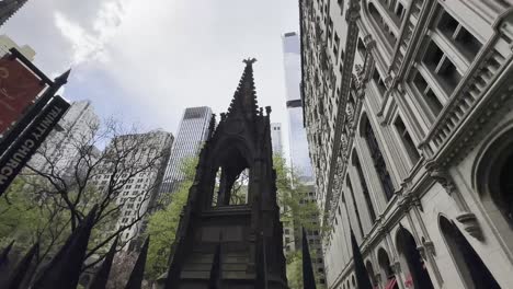 A-captivating-view-of-Trinity-Church-in-Lower-Manhattan,-framed-by-towering-modern-skyscrapers,-showcasing-the-contrast-between-historic-and-contemporary-architecture-on-a-partly-cloudy-day