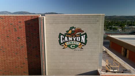 Aerial-view-around-the-Canyon-Cowboys-logo-on-a-building-wall-in-sunny-Santa-Clarita,-CA,-USA