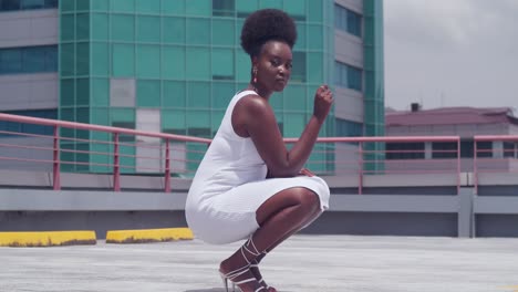 On-a-rooftop-overlooking-the-city,-a-young-black-girl-wears-a-white-dress