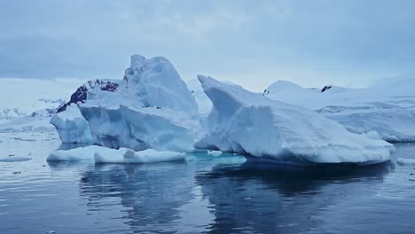 Icebergs-De-Hielo-Azul-En-La-Antártida,-Formación-De-Hielo-Flotando-En-El-Agua-Del-Mar-En-El-Hermoso-Paisaje-Invernal-De-La-Península-Antártica,-Formas-Asombrosas-En-La-Naturaleza-En-La-Escena-Costera