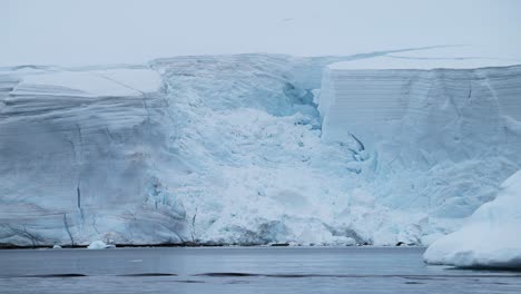 Glacier-and-Ocean-in-Antarctica-on-the-Coast,-Ice-and-Coastal-Winter-Scenery,-Icy-Glacial-Landscape-with-a-Large-Glacier-Next-to-the-Sea-on-the-Antarctic-Peninsula-with-a-Crevass-and-Ice-Formations