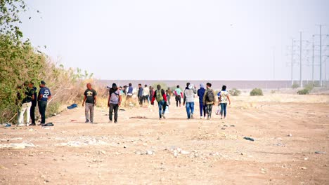 Migrantes-Con-Agua-Y-Comida-Junto-Al-Muro-Fronterizo