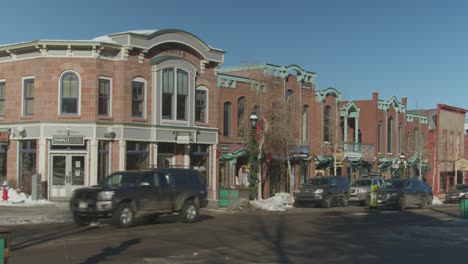 Red-brick-building-in-Downtown-Denver,-Colorado,-USA-with-cars-and-people-passing-by-on-a-cold-winter-morning