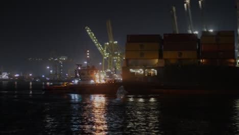 Toma-Cinematográfica-En-Movimiento-Pasando-Por-Un-Buque-Portacontenedores-Por-La-Noche-Y-Vista-Del-Puerto,-Puerto-Autónomo-De-Dakar---Puerto-Autónomo-De-Dakar,-Senegal