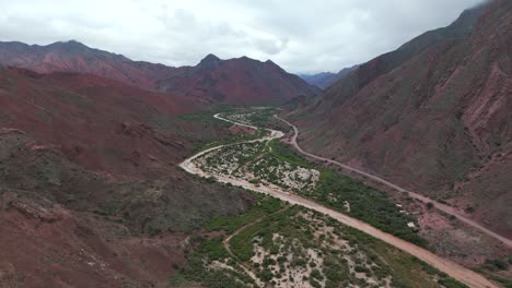 Quebrada-de-las-conchas-in-Cafayate,-Salta-with-lush-greenery-and-red-mountains,-aerial-view