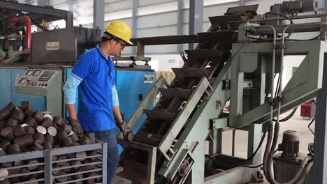 Worker-pouring-forging-plant-raw-material-inside-the-machine,-Industrial-safety-first-concept