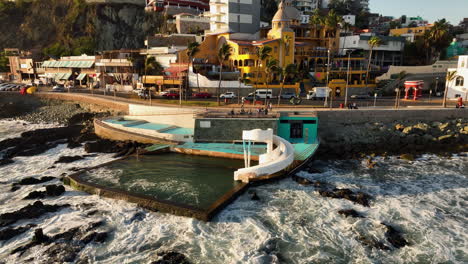 Aerial-view-circling-a-waterslide-on-the-coast-of-Mazatlan,-golden-hour-in-Mexico