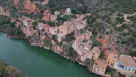 Miravet,-Eine-Malerische-Stadt-Mit-Bunten-Häusern-Auf-Einer-Klippe-Am-Fluss,-Luftaufnahme