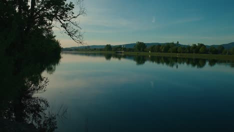 Ruhiger-See-Mit-Baumreflexionen-Und-Bergen-Im-Hintergrund-Bei-Sonnenuntergang-Im-Jarun-See,-Zagreb,-Kroatien