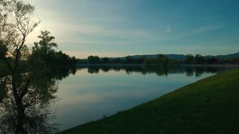 Serene-lake-with-tree-reflections-and-mountains-in-the-background-at-sunset-in-Jarun-Lake,-Zagreb-Croatia