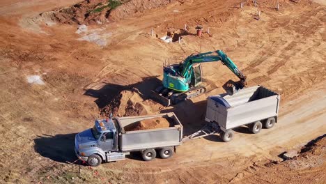 Tracked-excavator-on-a-dirt-pile-loading-a-truck-and-trailer