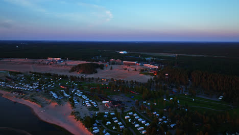 Drone-overlooking-the-beach,-campground-and-hotels,-sunset-in-Kalajoki,-Finland