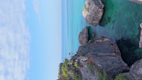 Vertikale-Videodrohne-Vor-Der-Felsigen-Küste,-Horizontblick-über-Das-Türkisfarbene-Meer