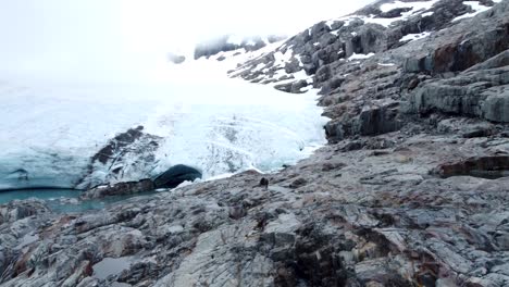 Drone-revealing-people-walking-up-to-Brewster-Glacier-at-Brewster-Track-in-Mount-Aspiring-National-Park,-New-Zealand