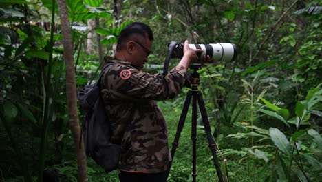 Fotógrafo-De-Vida-Silvestre-Usando-Teleobjetivo-Con-Ropa-De-Camuflaje-Sujetando-Su-Carema-Al-Trípode