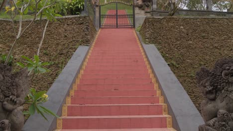 The-striking-red-staircase-of-Pura-Gunung-Kawi-Sebatu-in-Bali,-Indonesia,-surrounded-by-greenery