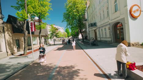 Footage-of-people-walking-and-wandering-through-Riga-Street-in-Daugavpils-during-spring,-capturing-the-vibrant-atmosphere-and-local-architecture