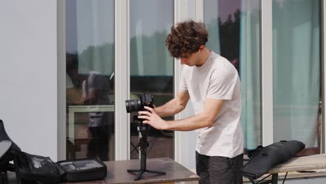 Male-attach-camera-on-gimbal-stabilizer-near-reflective-building-window