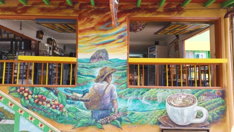 Toma-Panorámica-Del-Restaurante-Guatapé-Con-Pintura-Artística-Temática-De-Café-En-La-Fachada,-Colombia