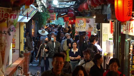 Jiufen-Old-Street,-a-captivating-Taiwan-mountain-village,-comes-alive-with-people-thronging-the-narrow-laneway,-exploring-the-vibrant-food-stalls,-souvenir-shops,-and-eclectic-gift-boutiques