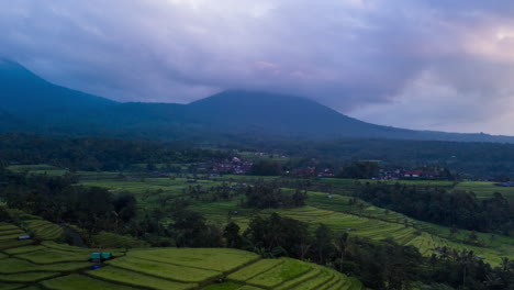 Terraced-rice-fields,-drone-hyper-lapse-with-moving-moody-clouds-at-sunrise-over-the-volcanic-hillsides-of-Jatiluwih,-Bali,-Indonesia