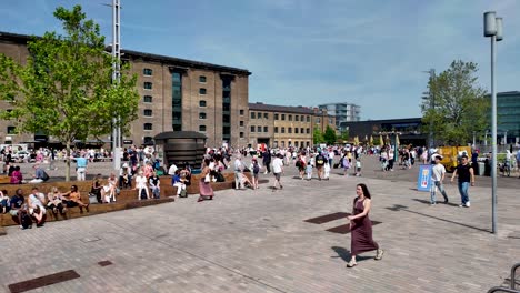 People-strolling-the-pedestrian-area-at-Granary-Square-in-Kings-Cross,-London,-on-a-sunny-day,-showcasing-the-concept-of-urban-leisure-and-social-interaction