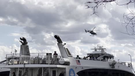 Un-Clip-Dinámico-Que-Captura-Un-Ferry-De-La-Ciudad-De-Nueva-York-Y-Un-Helicóptero-En-El-Aire,-Con-Un-Telón-De-Fondo-De-Nubes-Dramáticas,-Destacando-La-Bulliciosa-Escena-Del-Transporte-En-Nueva-York.