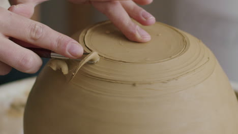 Removing-material-from-a-clay-vase-during-pottery,-vase-on-a-potters-wheel