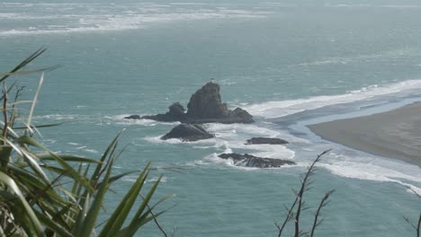 Rocks-and-lighthouse-on-Whatipu-Beach,-Omanawanui,-New-Zealand