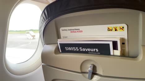 Swiss-Air-safety-instructions-and-airplane-seat-near-window-inside-an-airplane-in-Switzerland,-traveling-in-Europe,-4K-shot