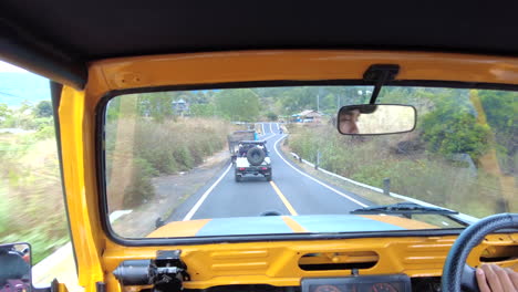 POV-Driving-in-a-yellow-jeep-on-a-road-in-Bali,-Indonesia