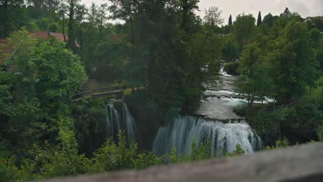 Lush-green-landscape-with-cascading-waterfalls-and-rustic-bridges-in-Rastoke,-Croatia