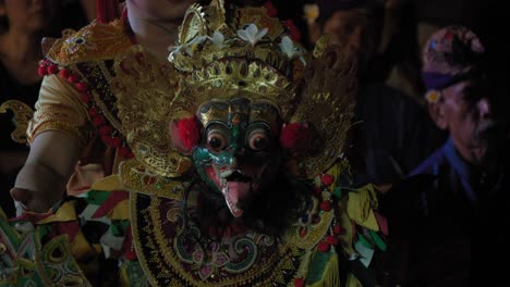 Un-Artista-Balinés-En-Una-Danza-Tradicional-Barong,-Con-Una-Máscara-Ornamentada-Y-Un-Traje-Ricamente-Decorado