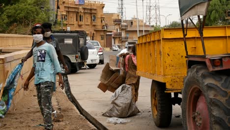 two-cleaners-throwing-pile-of-garbage-in-the-truck