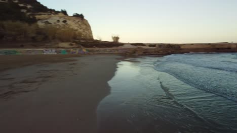 Wellen-Schlagen-Gegen-Einen-Mit-Graffiti-Bedeckten-Strand-In-Costa-Garaf,-Barcelona