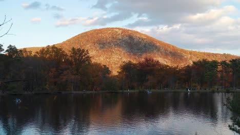 Zeitraffer-Des-Sonnenuntergangs-Am-Bear-Mountain-Lake.-Menschen-Fahren-An-Einem-Windigen-Tag-Tretboot-Mit-Bergen-Im-Hintergrund