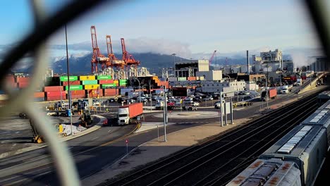 LKWs-Transportieren-Intermodale-Frachtcontainer-In-Einem-Geschäftigen-Frachthafen-Mit-Eisenbahnwaggons-Und-Ladekränen