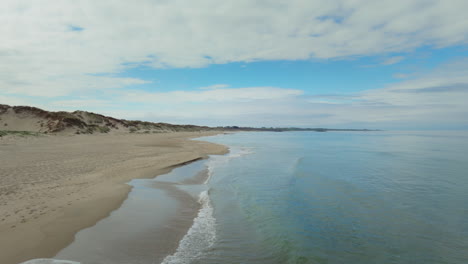 Low-aerial-shot-of-waves-crashing-onto-a-beautiful-beach-in-Norway