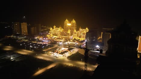 Vista-Aérea-De-Un-Edificio-Brillantemente-Iluminado-Por-La-Noche-En-La-Zona-Económica-Especial-De-Boten,-Cerca-De-La-Frontera-Entre-Laos-Y-China,-Muestra-El-Concepto-De-Desarrollo-Moderno-Y-Una-Vibrante-Vida-Nocturna.