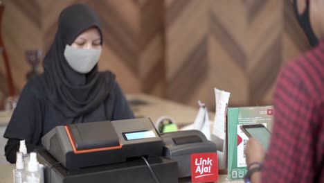 West-Java-Indonesia,-December-1,-2021-:-A-man-makes-a-payment-by-showing-his-cellphone-to-a-cashier-in-a-cafe