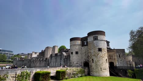 Daytime-view-of-Byward-Tower-in-the-Tower-of-London-complex,-visitors-traversing-the-bridge,-architectural-heritage-and-tourism-activity,-concept-of-historical-exploration-and-cultural-significance