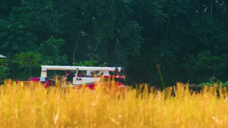 Modern-Harvester-Vehicle-passing-by-an-Rice-Paddy-Field,-Bangladesh