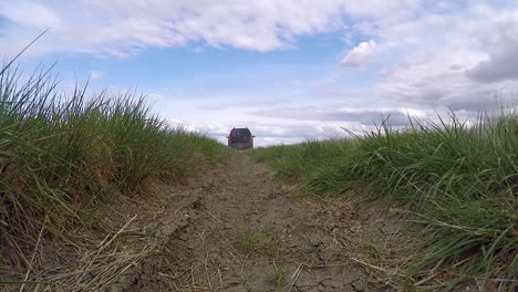 Vista-Posterior-Conduzca-Sobre-La-Cámara-Por-Un-Sucio-Nissan-Xterra-En-Un-Campo-Rural-Lleno-De-Baches-En-Las-Praderas-Canadienses