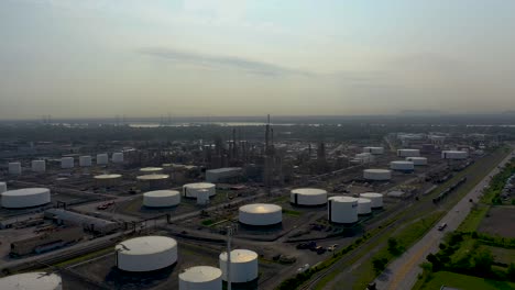 Drone-shot-moving-towards-on-an-oil-refinery-in-a-summer-sky-in-Montreal,-Quebec,-Canada