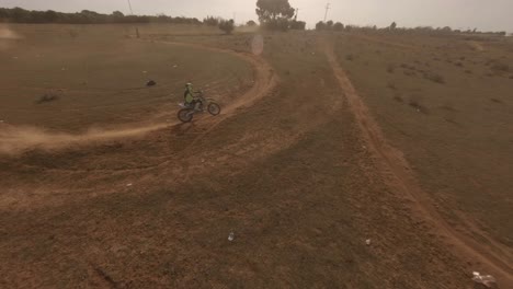 La-Cámara-FPV-Sigue-Al-Motociclista-En-Una-Pista-De-Arena-Polvorienta-En-Un-Día-Soleado-Y-Dorado