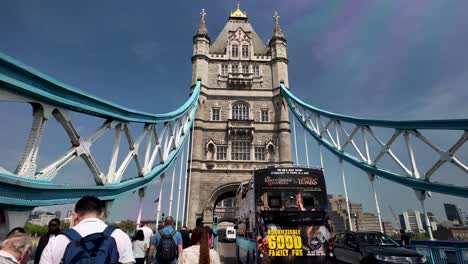 Dynamic-view-of-people-and-car-traffic-crossing-Tower-Bridge,-an-iconic-London-landmark,-bustling-with-activity,-the-concept-of-urban-movement-and-connectivity