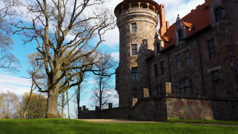 Back-side-of-Cesvaine-Castle-with-Tower-and-Tree-in-low-angle-approaching-shot