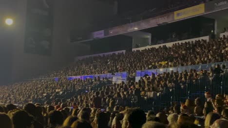 crowds-of-people-watching-and-cheering-with-an-evening-full-of-laughter,-music-and-comedy-as-you-tune-in-to-Gilmário-Vemba's-show,-surrounded-by-the-warm-glow-of-the-lights