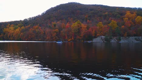 Scenic-Autumn-Lake-With-People-Pedal-Boating-In-Front-Of-A-Mountain