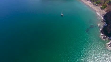 Luftbildvideo-Eines-Einrumpfsegelboots,-Das-In-Einer-Leeren,-Ruhigen-Bucht-Vor-Anker-Liegt-Und-Sich-Nach-Oben-Neigt,-Um-Einen-Wunderschönen-Sandstrand-Im-Paradies-Freizugeben